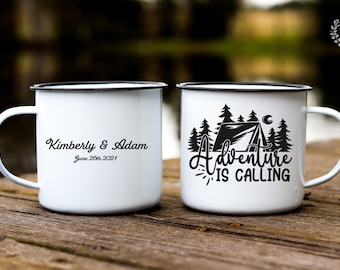Puede incluir: Dos tazas de esmalte blanco con bordes negros. Una taza tiene el texto "Kimberly & Adam June 26th, 2021" y la otra taza tiene una ilustración en blanco y negro de una tienda de campaña en un bosque con el texto "Adventure is Calling".