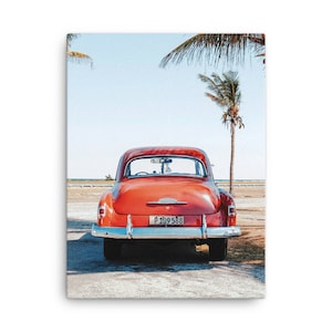 May include: A red vintage car parked on a sandy beach with palm trees in the background. The car has a number plate that reads "P 109 588".