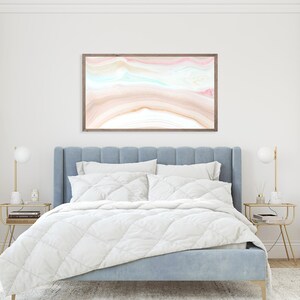 May include: A light blue upholstered bed with a white duvet and a framed abstract painting above the headboard. The painting features a pink, blue, and brown abstract design.