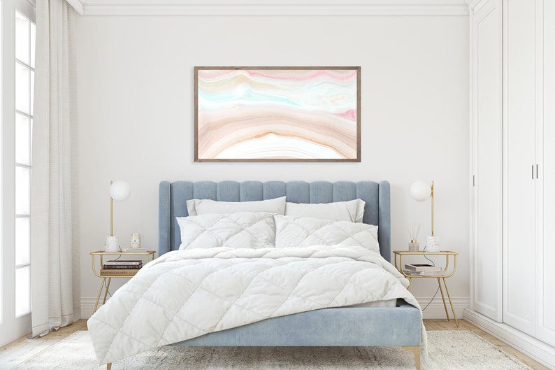 May include: A light blue upholstered bed with a white duvet and a framed abstract painting above the headboard. The painting features a pink, blue, and brown abstract design.