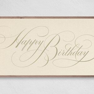 May include: A framed print with a beige background and a cursive script that reads "Happy Birthday".