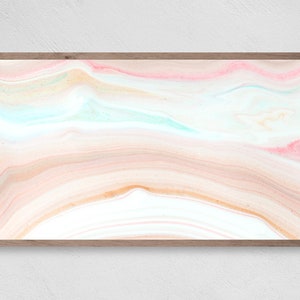 May include: Abstract art print with a swirling pattern of pink, peach, and blue colors. The print is framed in a light wood frame.