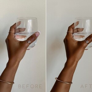 May include: A hand holding a clear glass of water with a gold bangle bracelet on the wrist. The hand is wearing a gold ring with a small diamond on the index finger.