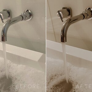 May include: A chrome bathroom faucet with a single handle is mounted to a white wall. Water is flowing from the faucet into a white bathtub filled with bubbles.