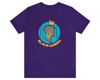 Op de afbeelding: Een paars t-shirt met een grafisch ontwerp. Het ontwerp toont het profiel van een persoon met een gouden kroon en oorbel in een turquoise cirkel. De woorden "BLACK QUEEN" zijn in goud.