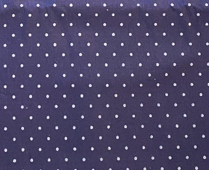May include: A dark navy blue fabric featuring a repeating pattern of small, evenly spaced white polka dots arranged in a grid-like formation across the entire surface of the material, creating a consistent and uniform visual texture throughout.