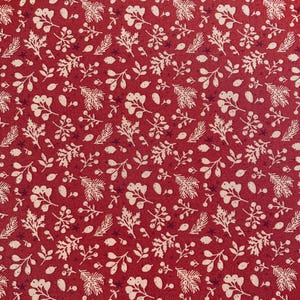 May include: Close-up of a red fabric with a repeating pattern of white botanical elements. The design includes leaves, berries, and sprigs, creating a festive and natural aesthetic. The fabric has a textured appearance.