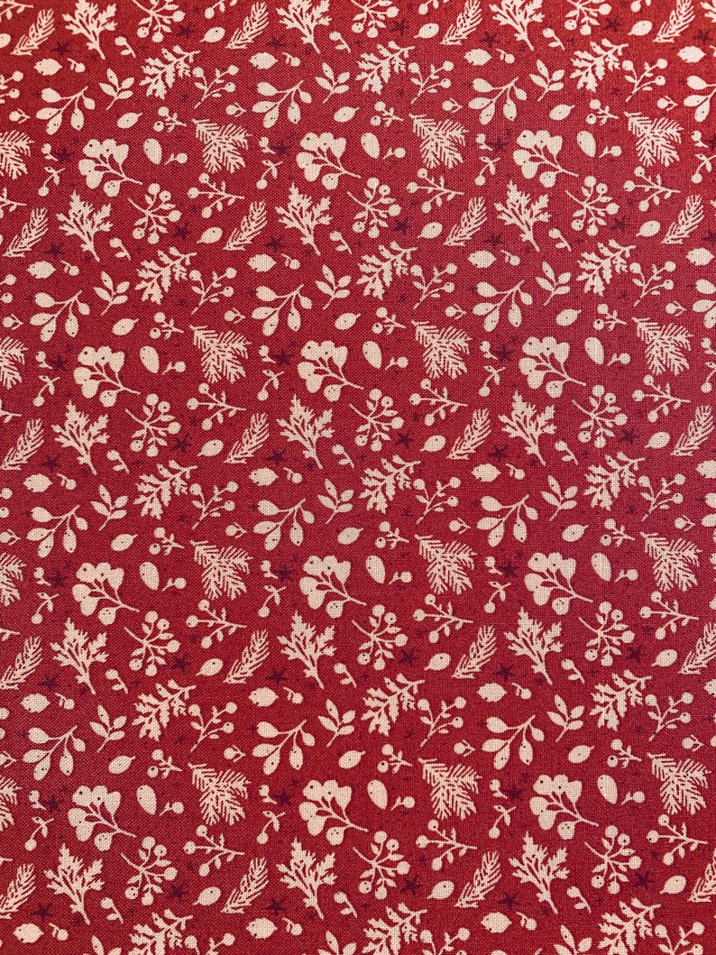 May include: Close-up of a red fabric with a repeating pattern of white botanical elements. The design includes leaves, berries, and sprigs, creating a festive and natural aesthetic. The fabric has a textured appearance.