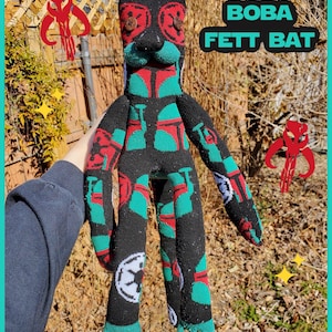 May include: A handmade plush bat doll in black, red, and teal, inspired by Boba Fett. The doll has button eyes and a Star Wars symbol on its leg. The text "BOBA FETT BAT" is visible.