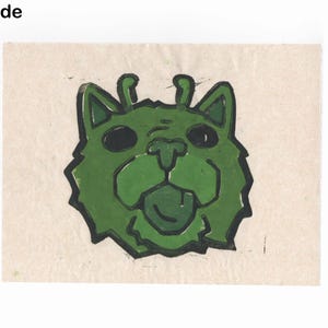 May include: A green cartoon cat face with black outlines and large black eyes. The cat has its tongue sticking out and two small antennae. The text "A Grade" is in the upper left corner.