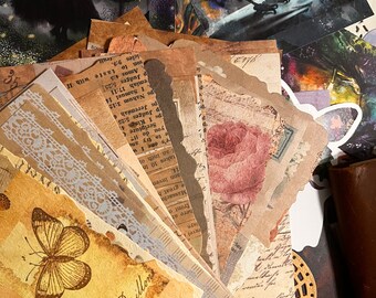 May include: A collection of vintage paper ephemera with a variety of designs, including butterflies, flowers, and lace. The papers are in shades of brown, beige, and white, and have a distressed, aged look.