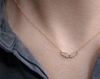 May include: A gold chain necklace with a delicate, diamond-encrusted angel wing pendant.