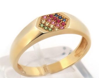 Può includere: Un anello d'oro con una faccia esagonale incastonata con una serie di pietre preziose colorate. L'anello ha una fascia liscia e lucida e un design geometrico. Le pietre preziose includono pietre rosse, blu, verdi e rosa.