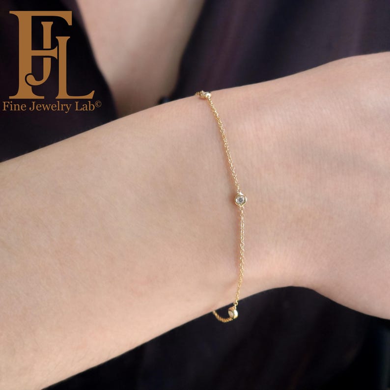 May include: A delicate gold chain bracelet with small round diamonds. The bracelet is on a person's wrist.