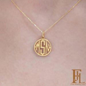 Peut inclure: Un collier avec un pendentif doré. Le pendentif circulaire présente les initiales "MSN" dans un design découpé. Le collier est suspendu à une fine chaîne. Les mots "Fine Jewelry Lab" sont imprimés en bas de l'image.
