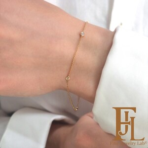 May include: A delicate gold chain bracelet with three small round diamonds. The bracelet is on a person's wrist.