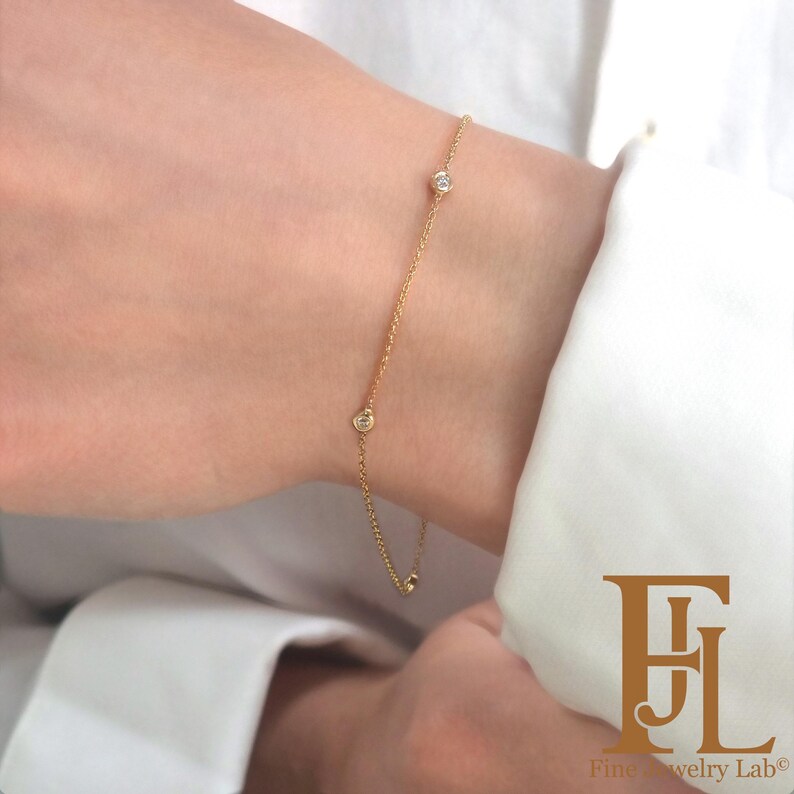 May include: A delicate gold chain bracelet with three small round diamonds. The bracelet is on a person's wrist.