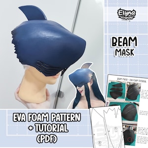 Può includere: Una maschera a forma di squalo blu navy realizzata in schiuma EVA. La maschera ha una pinna dorsale e branchie dettagliate. L'immagine include anche un modello PDF e un tutorial per creare la maschera, con il testo "BEAM MASK".