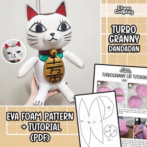 May include: A white cat figurine with red-tipped ears, black whiskers, and a gold bell collar. The cat holds a gold charm with black characters. The image includes a pattern and tutorial for the cat, with the text "EVA FOAM PATTERN + TUTORIAL (PDF)".