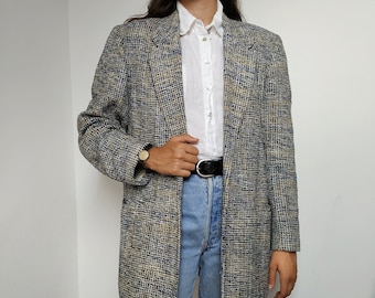 Puede incluir: Una chaqueta de tweed azul y blanca con un cinturón negro. La chaqueta tiene un corte clásico y un ajuste relajado.