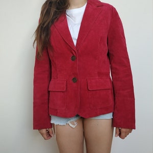 K&ouml;nnte beinhalten: Ein roter Wildlederblazer mit Knopfleiste und zwei Pattentaschen. Der Blazer hat lange &Auml;rmel und eine figurbetonte Silhouette.