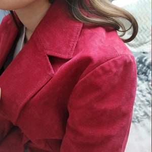 K&ouml;nnte beinhalten: Nahaufnahme einer roten Wildlederjacke mit Kragen und Knopfleiste.