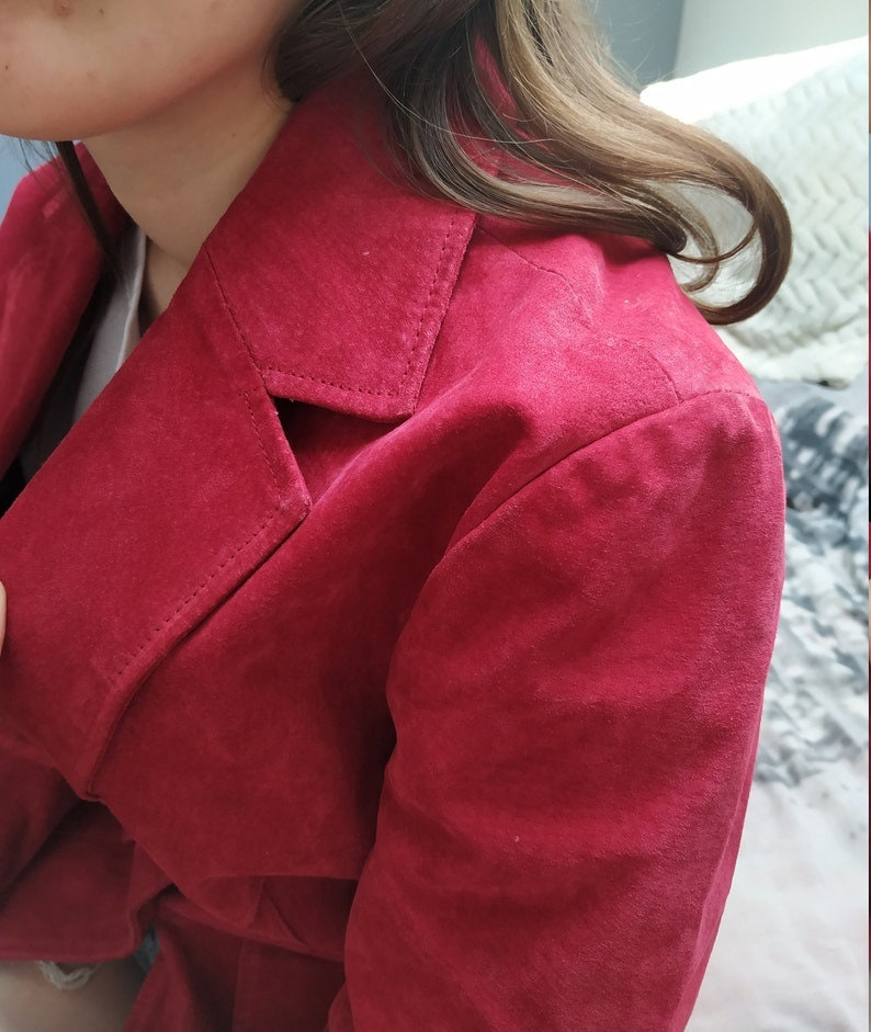 K&ouml;nnte beinhalten: Nahaufnahme einer roten Wildlederjacke mit Kragen und Knopfleiste.