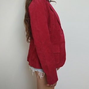 K&ouml;nnte beinhalten: Ein roter Wildlederblazer mit einem einzigen Knopfverschluss und einer Tasche auf der linken Seite.