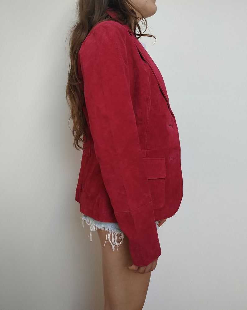 K&ouml;nnte beinhalten: Ein roter Wildlederblazer mit einem einzigen Knopfverschluss und einer Tasche auf der linken Seite.