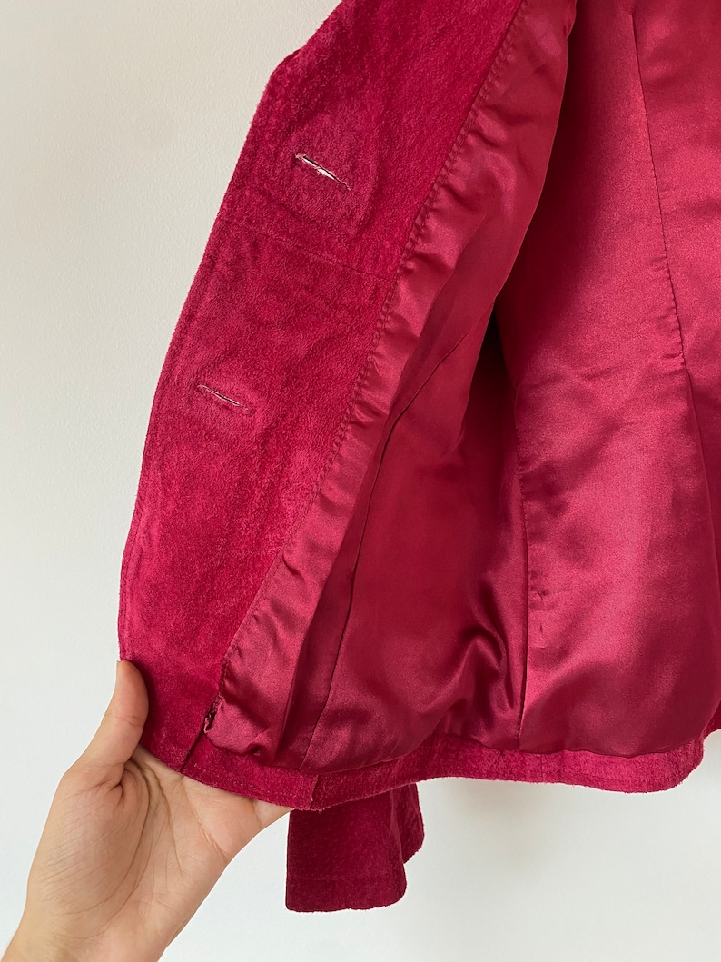 K&ouml;nnte beinhalten: Ein roter Samtblazer mit Satin-Futter. Der Blazer hat einen Knopfverschluss und lange &Auml;rmel.