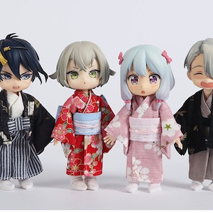 May include: Four small dolls wearing traditional Japanese clothing. The dolls are dressed in a black and gold kimono, a red and white kimono, a pink and white kimono, and a black and gold kimono with a grey obi.