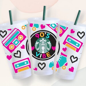May include: Three clear plastic cups with lids and straws, decorated with a 90's theme. The cups feature a pink and blue cassette tape, pink hearts, and a green and black Starbucks logo with the text "90's Vibe".