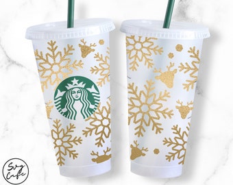 May include: Two clear plastic cups with gold snowflake and reindeer designs. The cups have lids and straws. The Starbucks logo is on one of the cups.