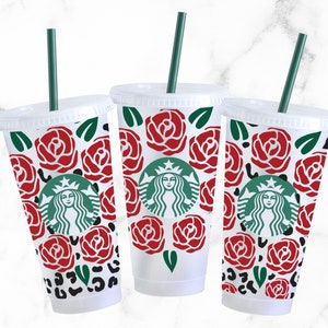 May include: Three clear plastic cups with green straws and red rose and leopard print designs. The cups feature the Starbucks logo with a green mermaid.