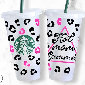 May include: Two white reusable cups with black and pink leopard print designs. One cup has the text "Hot Mom Summer" in a pink triangle.