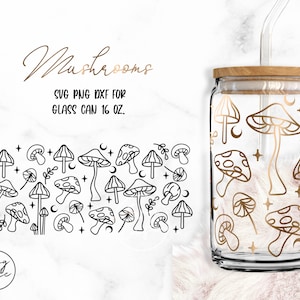 以下が含まれることがあります： 木製の蓋とストローが付いたガラス製の缶。缶には、キノコ、月、星を黒と白の線で描いた模様が描かれている。画像には「Mushrooms」と「SVG PNG DXF FOR GLASS CAN 16 OZ.」の文字が印刷されている。