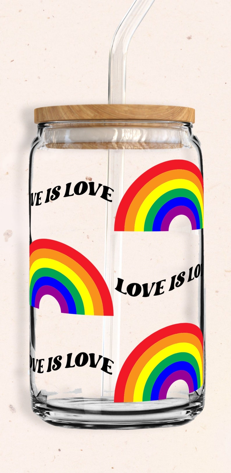 May include: A glass jar with a wooden lid and a glass straw. The jar has a rainbow design with the text "Love is Love" repeated on the jar.