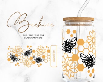 May include: A clear glass can-shaped tumbler with a wooden lid and a straw. The design features black bees, yellow honeycomb shapes, and floral elements. The text "Beehive" and "SVG / PNG / DXF FOR GLASS CAN 16 OZ" are also visible.