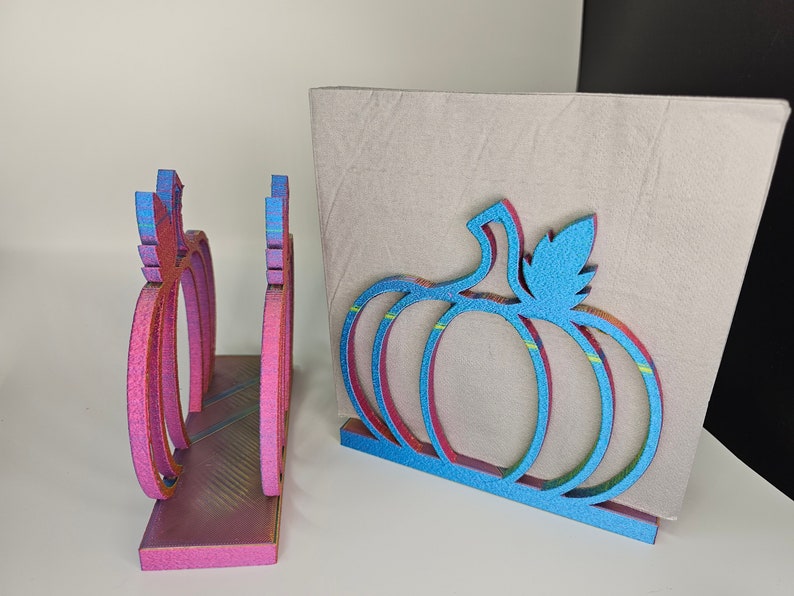 May include: Two wooden pumpkin napkin holders. One is pink with iridescent glitter and the other is blue with iridescent glitter.