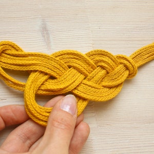 Pu&ograve; includere: Una corda intrecciata gialla annodata a forma di cuore.