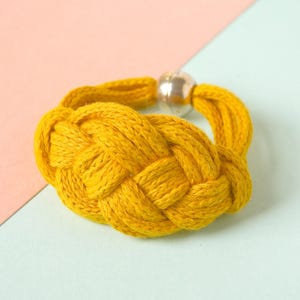May include: A yellow braided rope bracelet with a silver metal clasp.