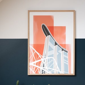 May include: A framed art print featuring a modern architectural illustration in shades of orange, white, and blue. The artwork is displayed on a wall painted in white and navy blue, with a collection of cacti in a dark gray planter below.