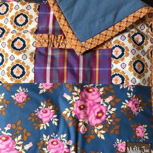 May include: A blue and brown patchwork quilt with a floral pattern and a Matilda Jane label. The quilt has a blue backing and a brown and white patterned border.