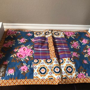 May include: A blue and white patchwork quilt with pink flowers and a brown border. The quilt has a "Matilda Jane" label.