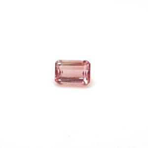 May include: A rectangular, faceted gemstone with a soft pink hue. The gem has a classic emerald cut, showcasing its clarity and internal structure. The stone is set against a plain white background, highlighting its color and shape.