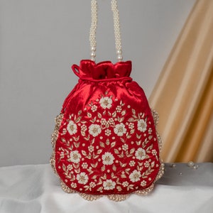 May include: A red velvet drawstring bag with a pearl handle and floral embroidery in gold and white.