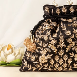 Könnte beinhalten: Eine schwarze Seiden-Kordeltasche mit goldener Stickerei und Pailletten. Die Tasche hat ein florales Design und zwei Quasten.