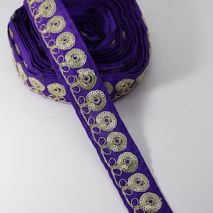 May include: Purple fabric trim with gold embroidered floral designs and sequins.
