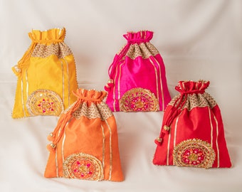 Può includere: Quattro sacchetti con coulisse in diversi colori: giallo, rosa, arancione e rosso. Ogni sacchetto ha bordi dorati e ricami intricati.