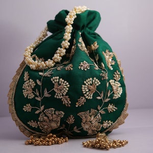 May include: A green drawstring bag with gold and white embroidery. The bag has a pearl chain handle and gold tassel accents.